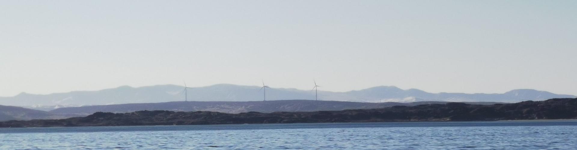 Meer und Bergkette am Horizont mit Windrädern