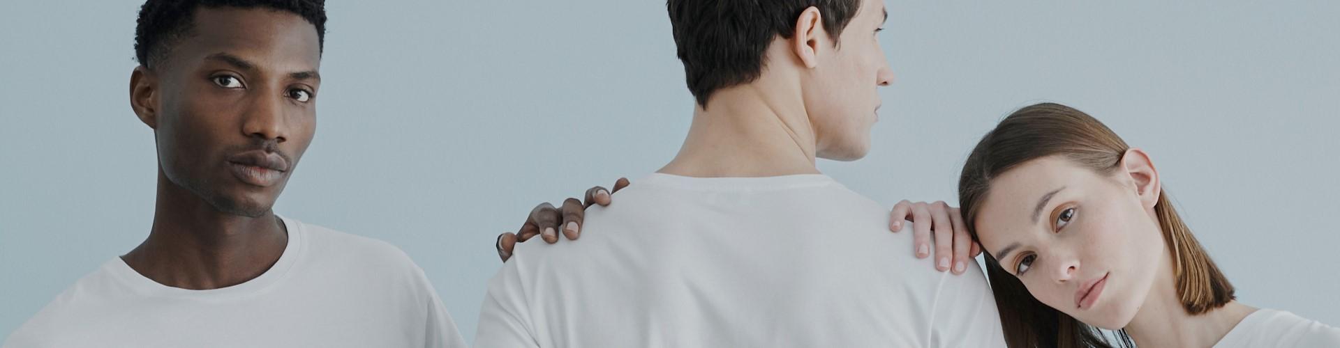 Drei Menschen in T-Shirt und Jeans stehen für ein Fotoshooting dicht beieinander