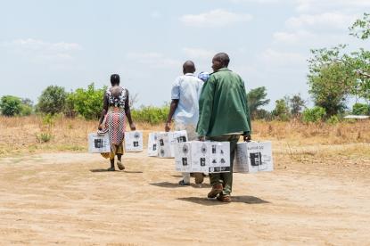 people in zambia carrying improved cookstove