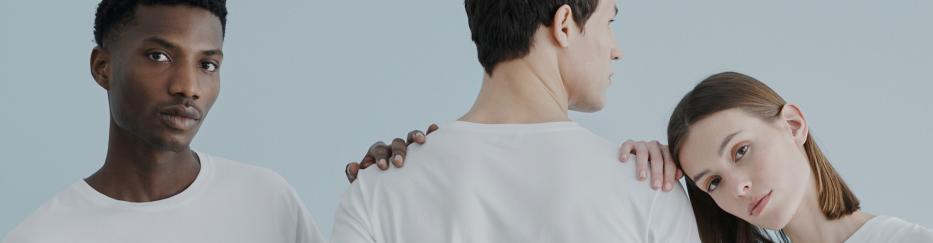 Drei Menschen in T-Shirt und Jeans stehen für ein Fotoshooting dicht beieinander