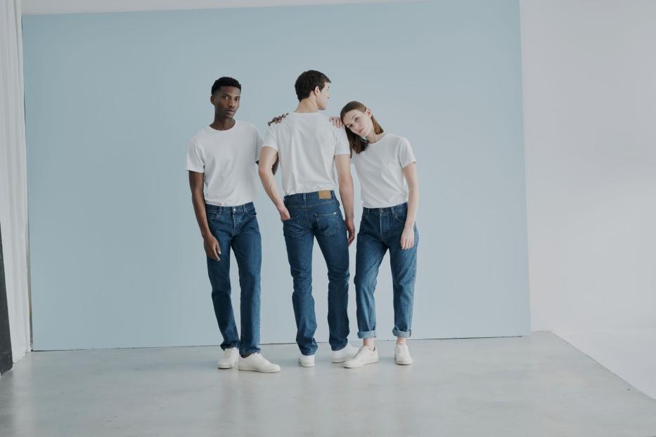 Drei Menschen in T-Shirt und Jeans stehen für ein Fotoshooting zusammen