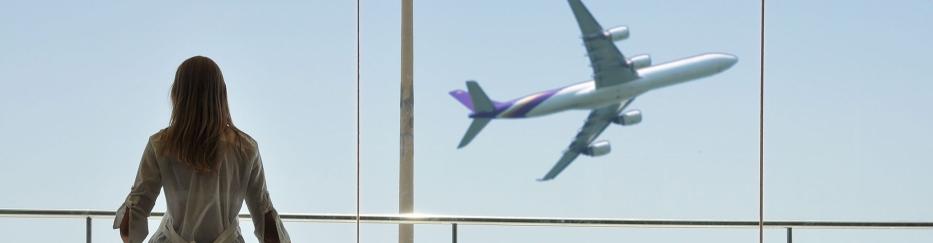 Frau schaut auf startendes Flugzeug